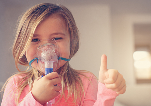 Cute girl using aerosol mask